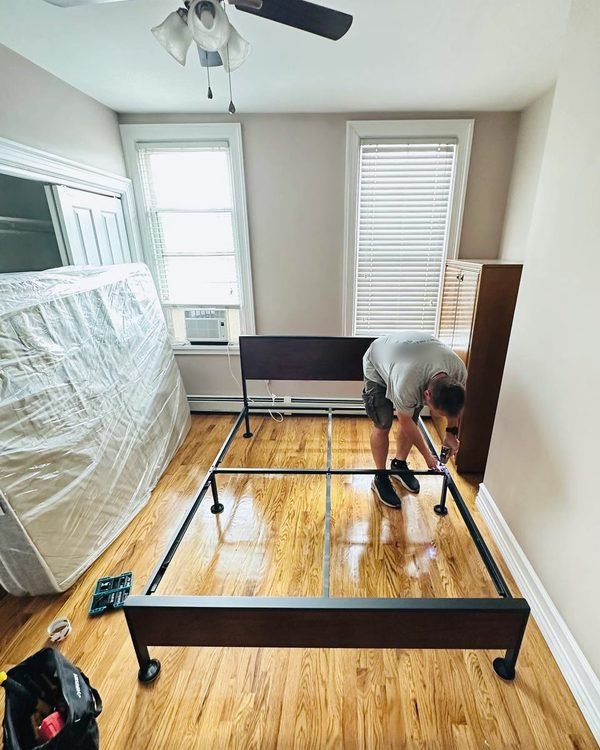 One of our movers putting a bed frame back together in a sunny bedroom