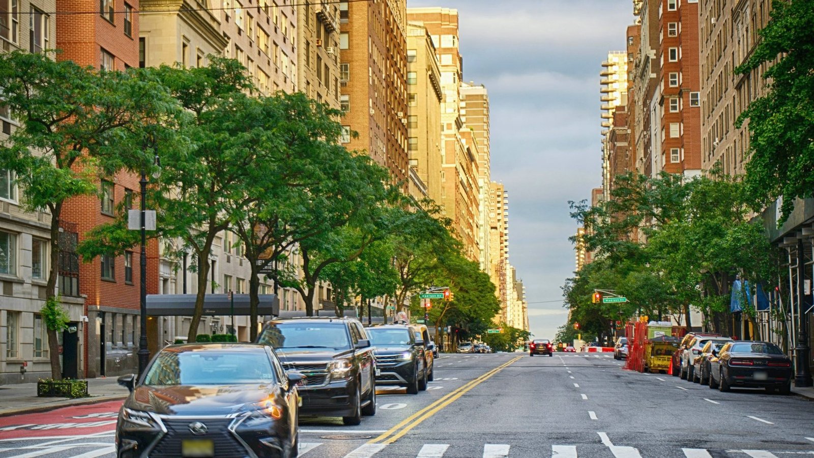A tree-lined avenue on the Upper East Side of Manhattan with prewar apartment buildings in late-day sun